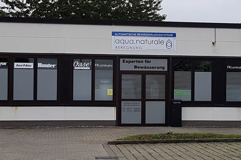 Fassade von aqua.naturale Beregnung an der Hammer Landstraße 113 in Neuss mit Firmenschild und Herstellerlogos an den Fenstern