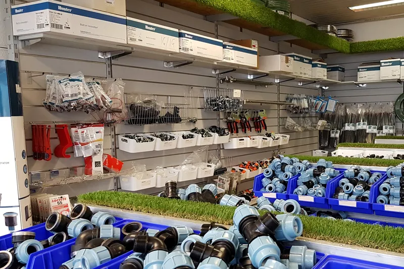 Verkaufsraum von aqua.naturale in Neuss mit Kisten voller PE-Klemmverbinder und Regalen mit Hunter-Ventilen und Zubehör
